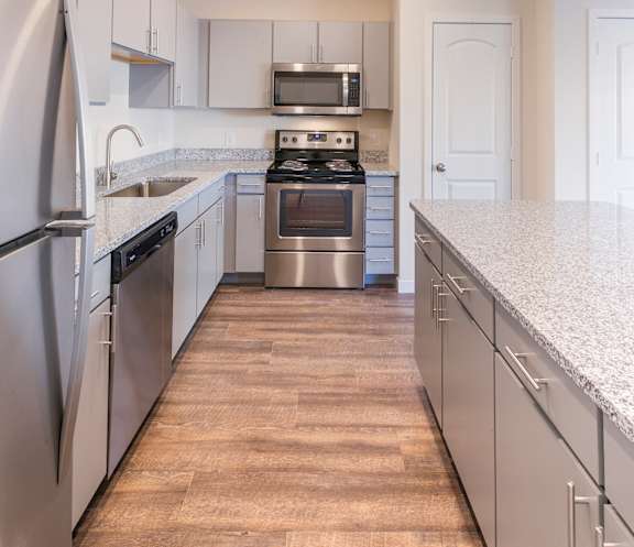 A modern kitchen with stainless steel appliances and wooden flooring.