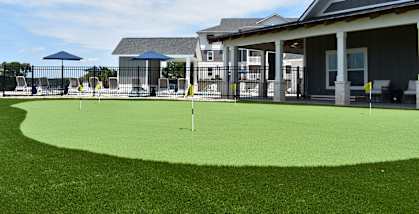 a putting green in front of a house with a clubhouse