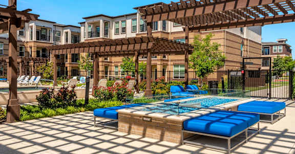 A pool area with a blue pool and sun loungers.