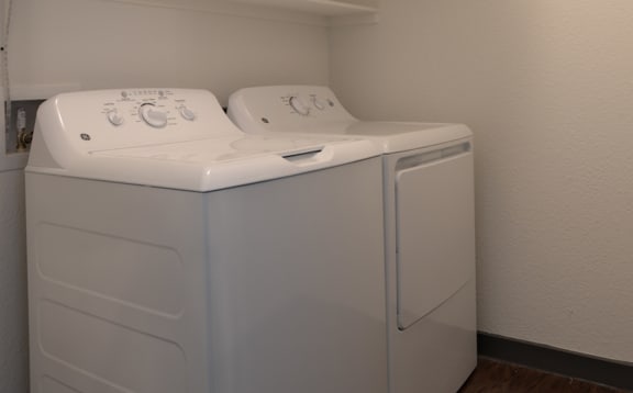 a white washer and dryer in a room with a shelf on the wall  at Epic Apartments, Denton, 76210