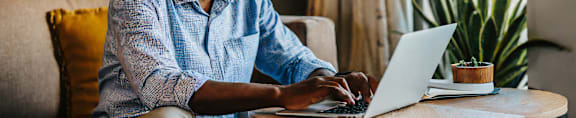 A man is sitting on a couch using a laptop.