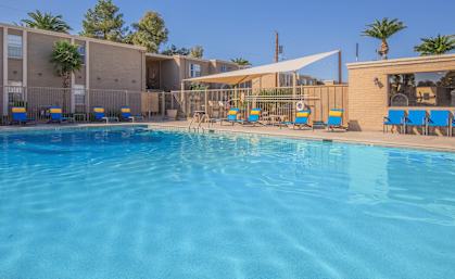 A large swimming pool in front of a building with sun loungers.