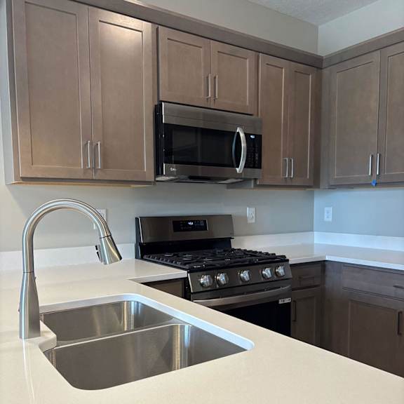 A kitchen with a stove, sink, and cabinets. at Ventura Townhouses, Michigan, 49460