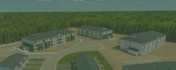 A bird's eye view of a housing complex with multiple buildings and a parking lot.