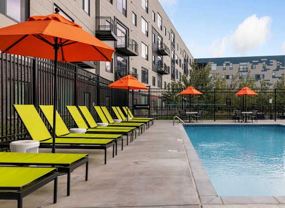 A pool surrounded by orange umbrellas and lounge chairs.