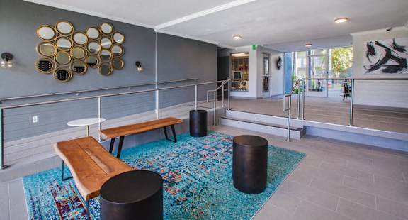 A room with a blue rug and a wooden bench.