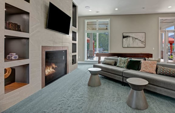 Living room at Ascent at Mallard Creek Apartment Homes. Carpet area with a fire place, tv, couch, pool table, tables, and big windows.