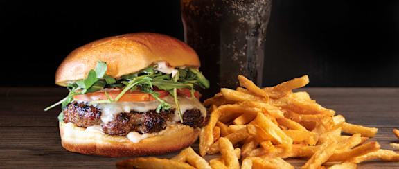 A close up of a burger with lettuce, tomato, and cheese.
