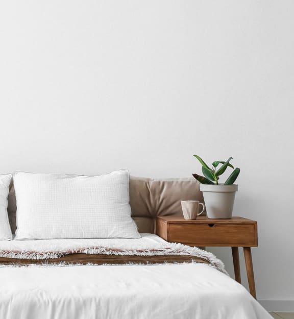 a white bedroom with a bed and two potted plants