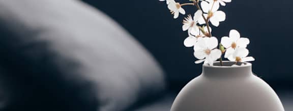 Three vases of different sizes are lined up on a table with a couch in the background.