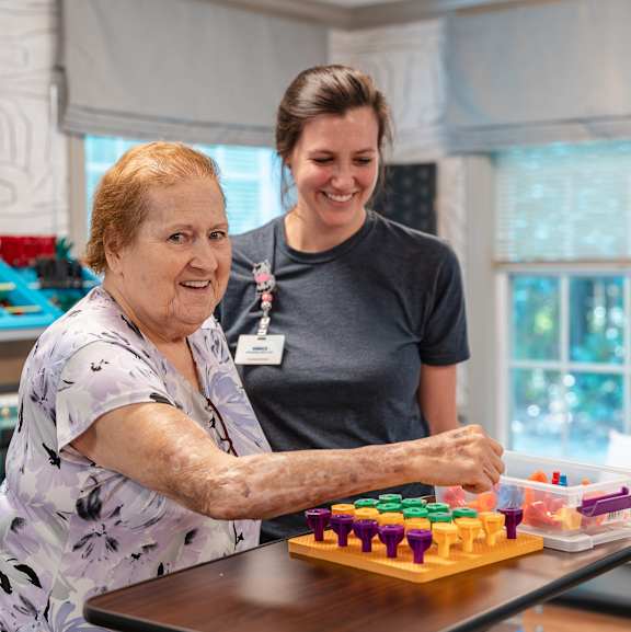 An elderly woman playing a board game with a younger woman.