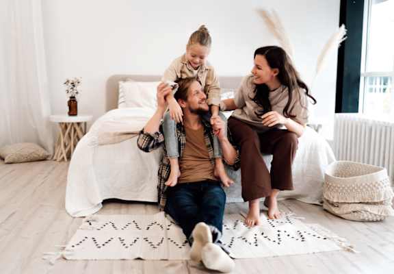 Family of Three Sitting on Floor in a Bright Bedroom