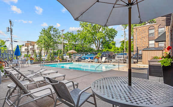 A pool area with chairs and an umbrella.