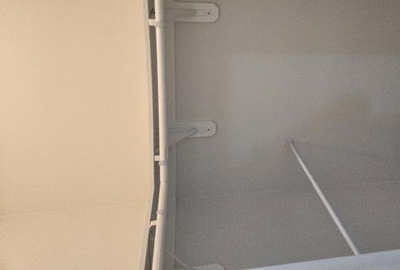 A white refrigerator with a brown carpet on the right side.