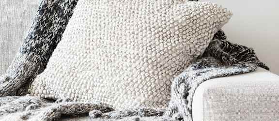 A grey couch with a blanket on it.