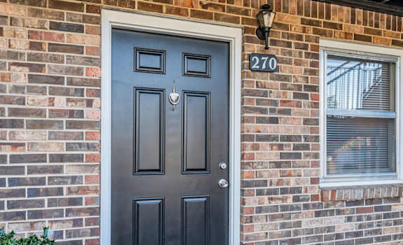 a brick house with a black door and a window
