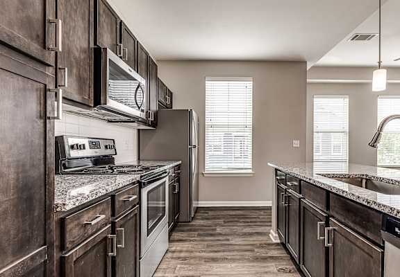 A kitchen with dark wood cabinets and granite countertops.