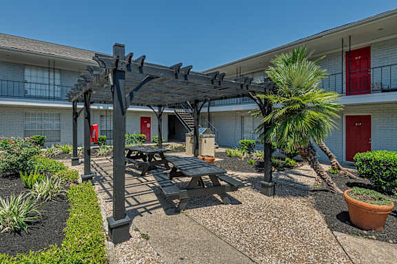 A patio with a table and chairs under a pergola.