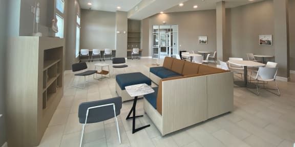 a large lobby with tables and chairs and a fireplace at City Square 162 Apartments