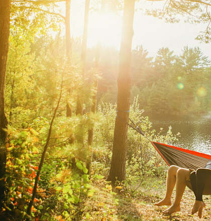 a couple relaxing in a hammock by a lake
