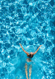 a woman swimming in a pool with blue water
