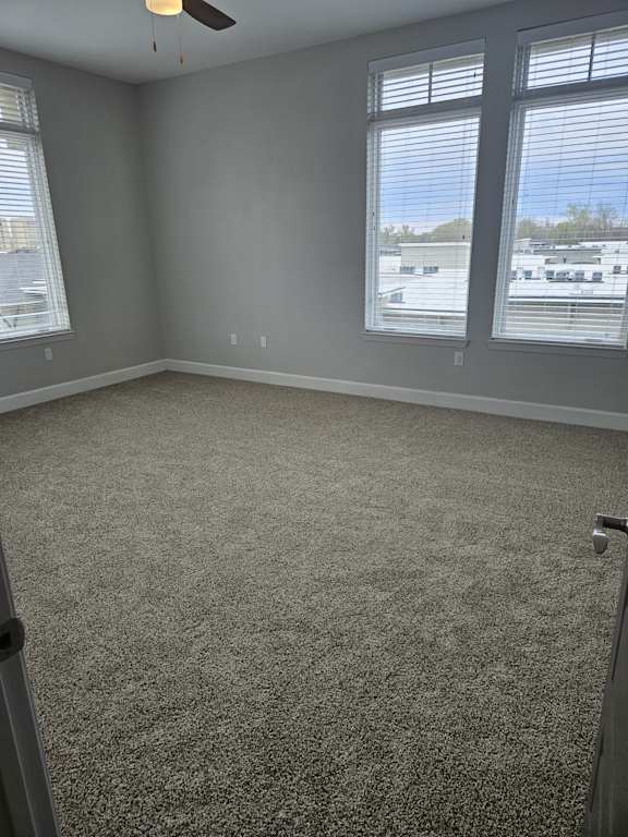 A room with a carpeted floor and a ceiling fan.