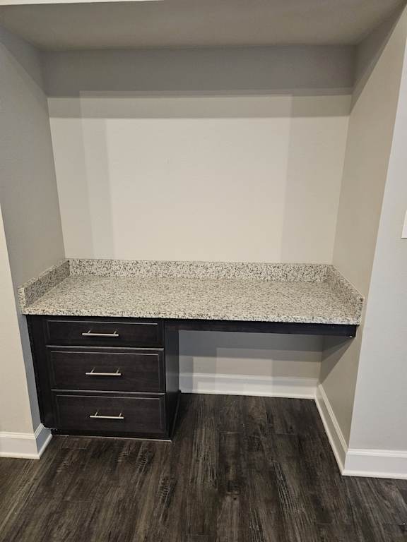 A black cabinet with two doors and two handles is placed against a wall with a textured surface.