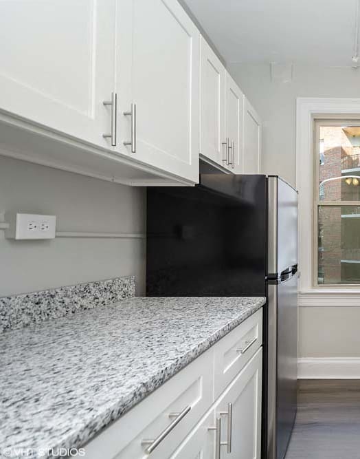 a kitchen with white cabinets and a window