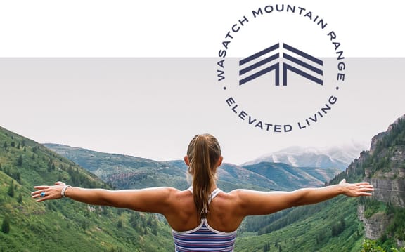 Woman looking over valley and the seven skies logo - Wasatch Mountain Range Elevated Living