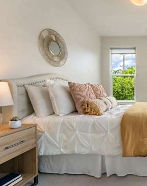 A bedroom with a large bed and a view of trees outside the window.