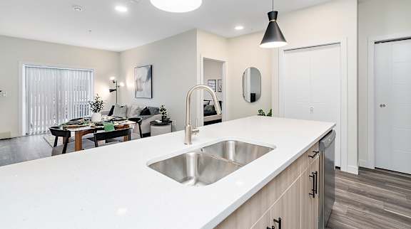A modern kitchen with a white countertop and stainless steel sink.