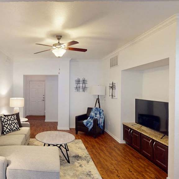 A living room with a couch, coffee table, plush chair, and TV at BRIO at Firewheel.
