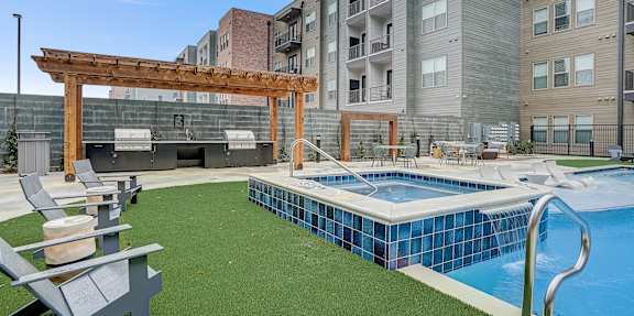 A large swimming pool is surrounded by a concrete deck and lounge chairs.