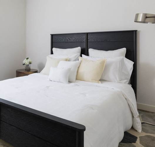 A bedroom with a large bed and a window with blinds.