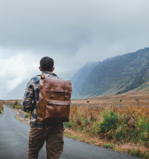 a man with a backpack walking down a road