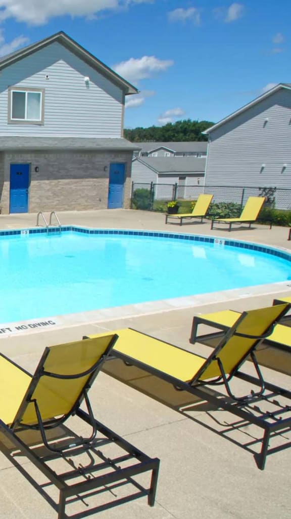 a large swimming pool with yellow chairs around it