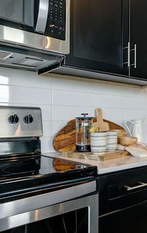 A modern kitchen with black cabinets and stainless steel appliances.