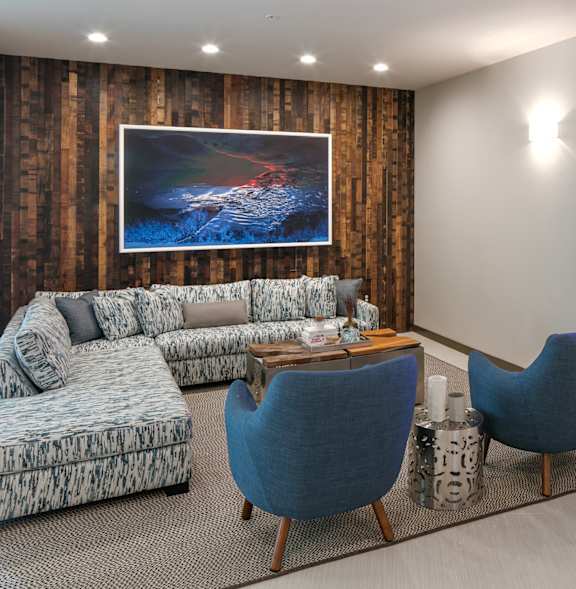 A living room with a couch, two chairs, and a television displaying a cartoon character.