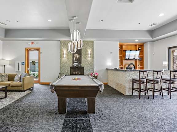 A room with a pool table and a bar area.