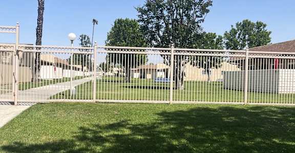A fenced area with a sign and a palm tree.