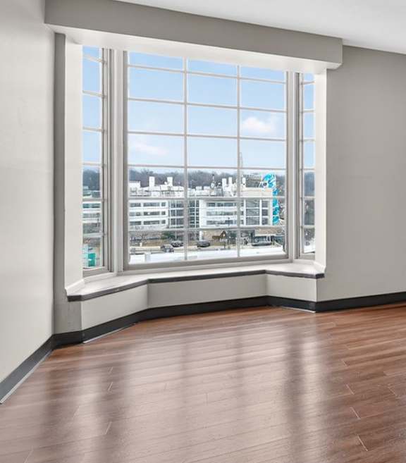A room with wooden floors and three windows.