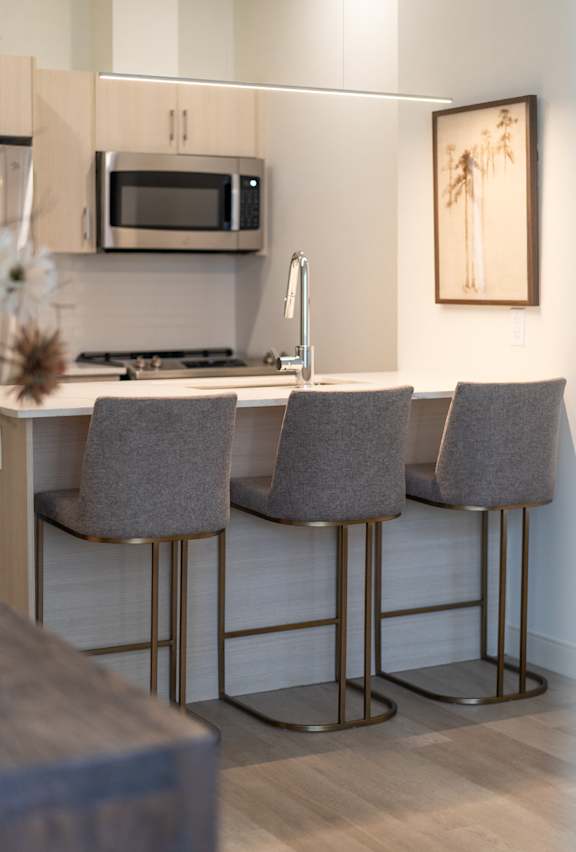A kitchen with a bar stool and a framed picture on the wall.
