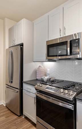 A kitchen with a stove top oven, microwave, and refrigerator.