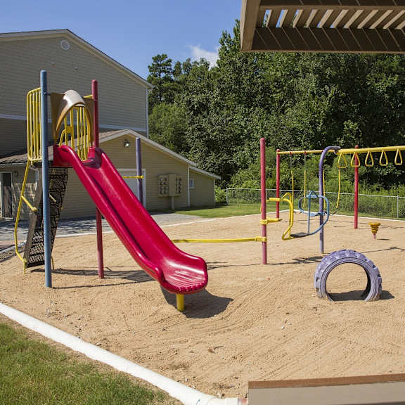 A playground with a red slide and a yellow and red climbing frame.