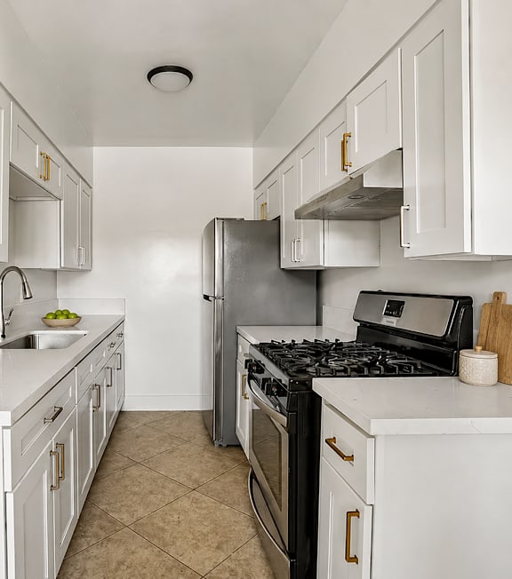 A kitchen with white cabinets and appliances, a stove top oven, and a microwave.