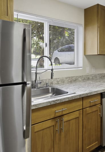 a kitchen with wooden cabinets and a stainless steel refrigerator  at Park 210 Apartment Homes, Edmonds, WA