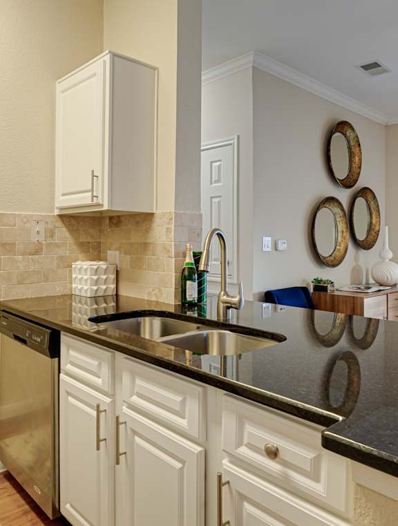 A kitchen with white cabinets and a black countertop.