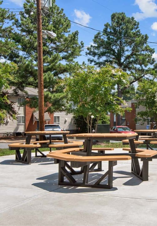 a group of picnic tables on a sidewalk in front of a building