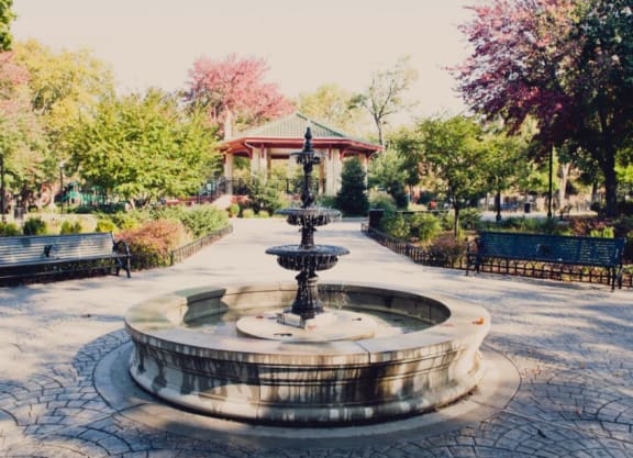 a fountain in a park with benches and a gazebo