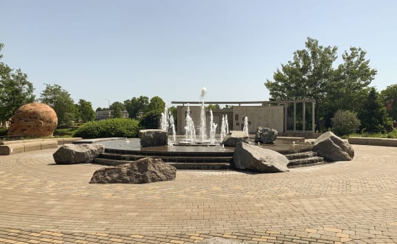 a sculpture in a park with a bridge in the background